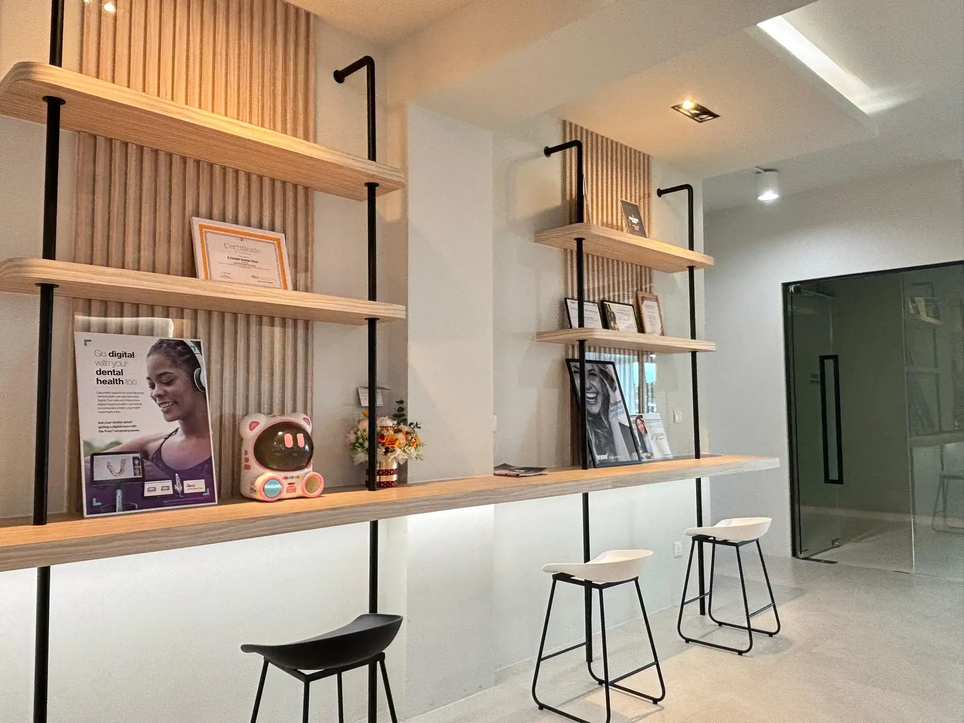 Modern lobby interior showcasing shelves with D Dentist's achievements and partner brands such as" Invisalign - in D Dentist's Tabuan Jaya branch.